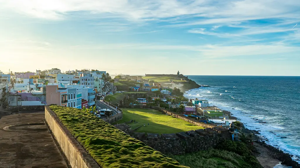 Old San Juan coastline, with colorful houses facing the sea and the walls of El Morro in the distance
